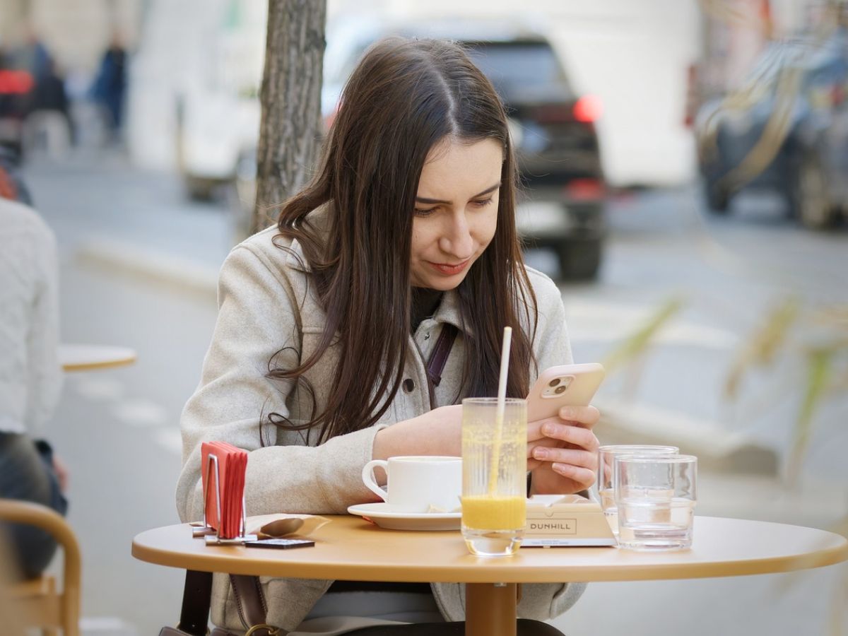 A woman checking her phone at a cafe table