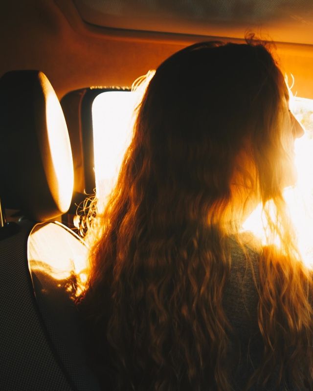 A woman driving toward the morning sun