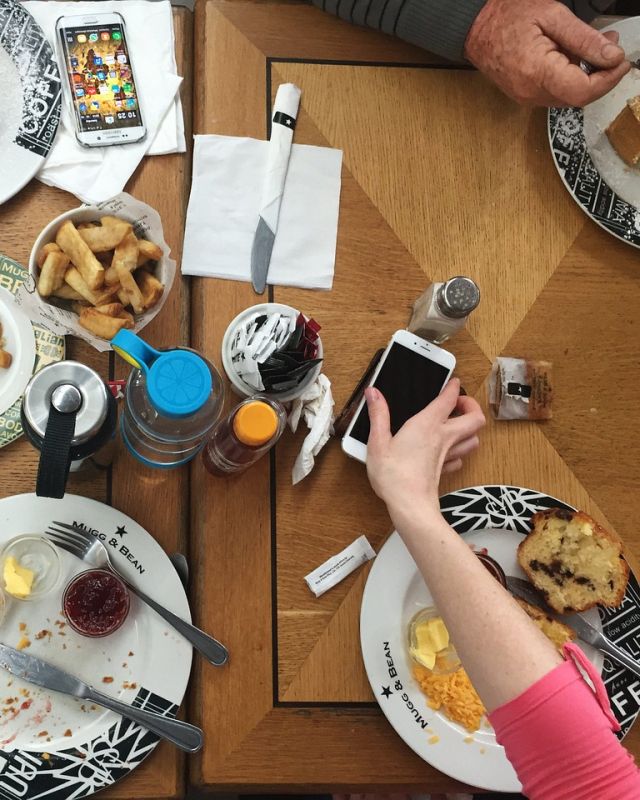A lunch table seen from above with a phone in hand