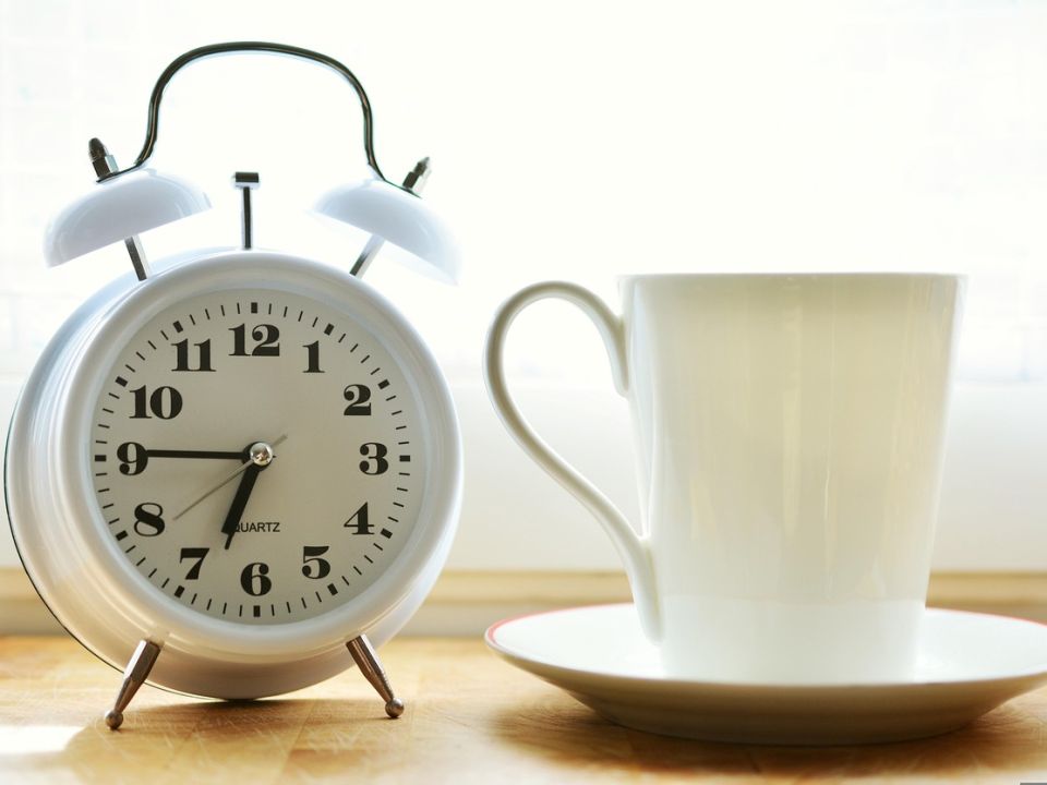An alarm clock and a cup of coffee