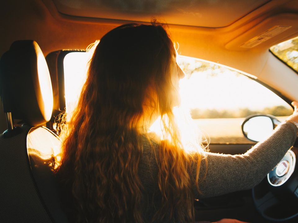 A woman driving into the morning sun