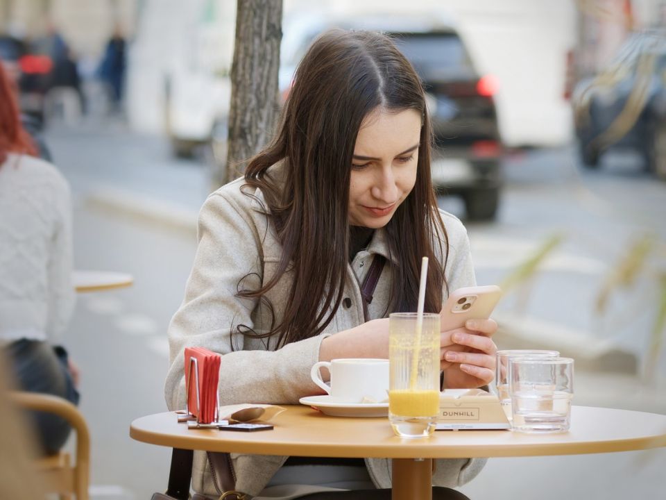 A woman checking email on her phone at a cafe