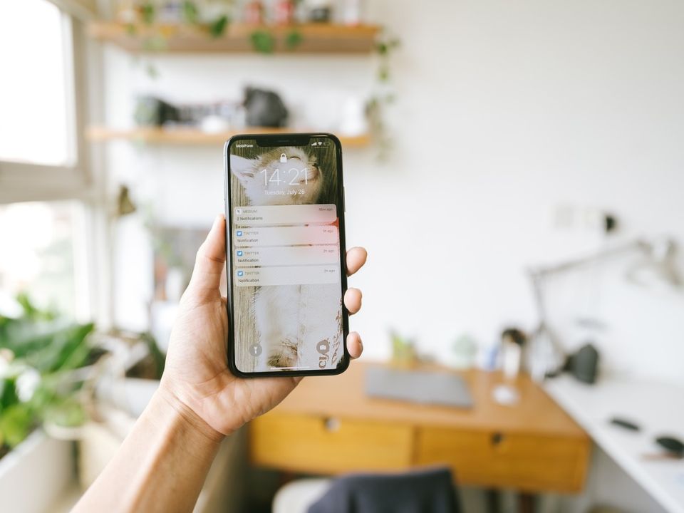 A hand holding a phone in a bright room