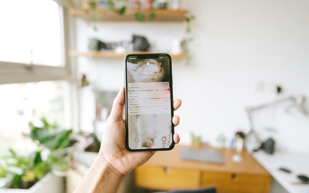 A hand holding a phone in a bright room