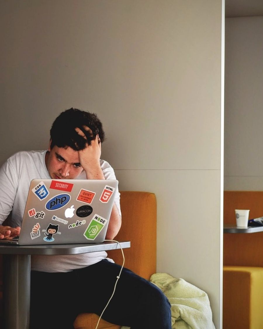 A man at his laptop with his head in his hand
